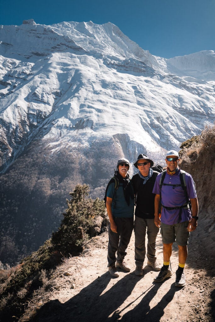 three men standing on a mountain with a mountain in the background