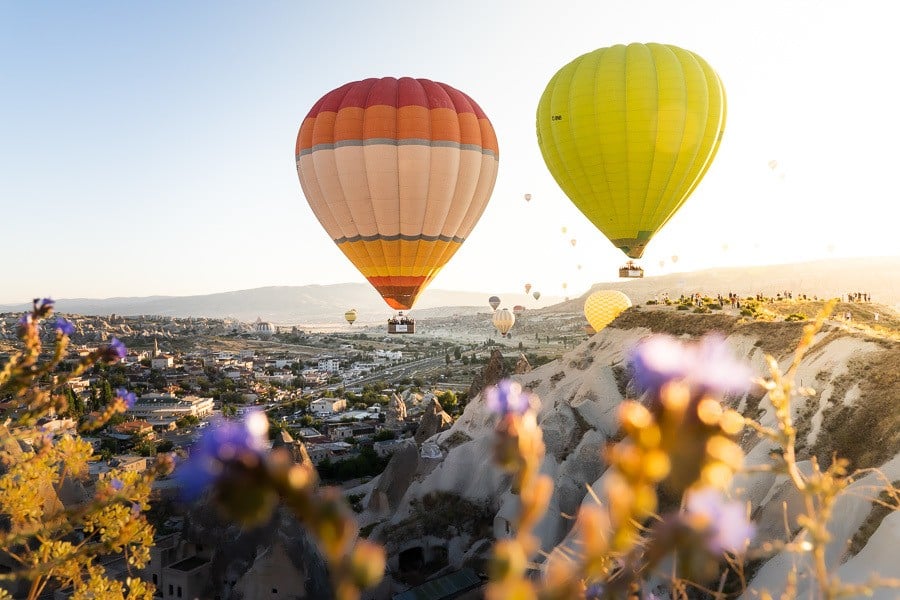 a couple of hot air balloons flying over a valley.