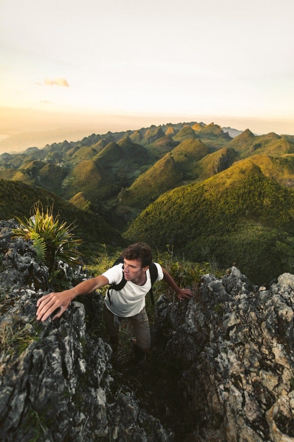 a man standing on top of a rocky hill.