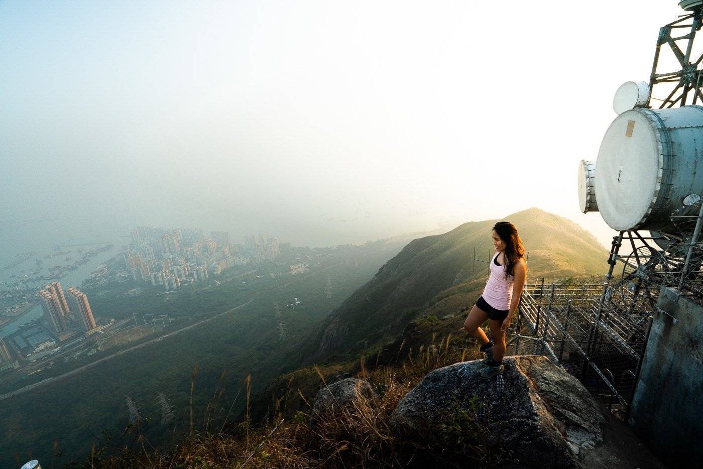 a woman standing on top of a mountain next to a radio tower.