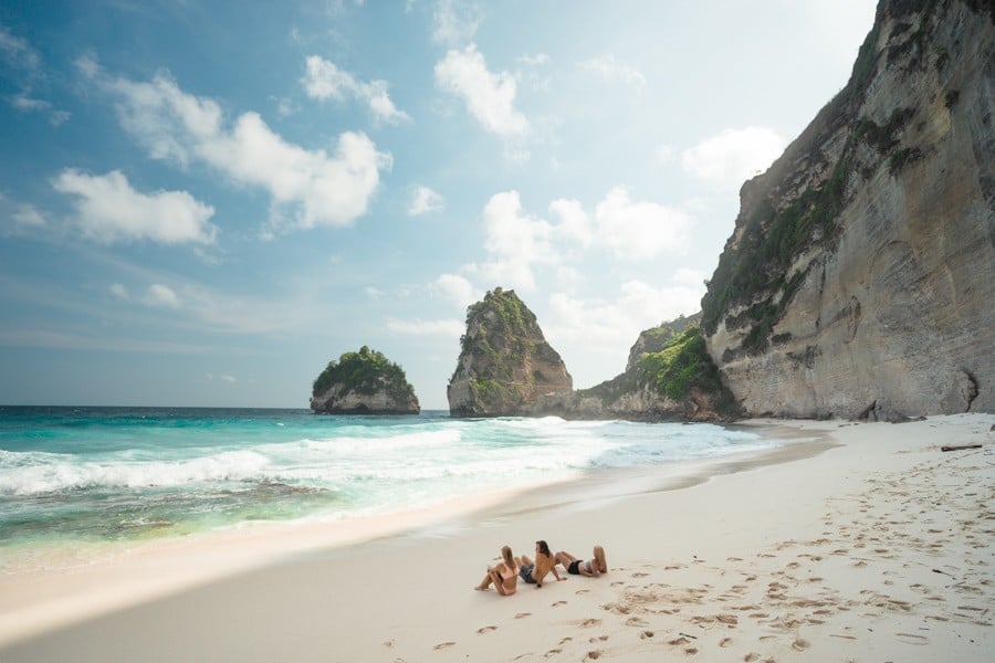 a group of people sitting on top of a sandy beach.