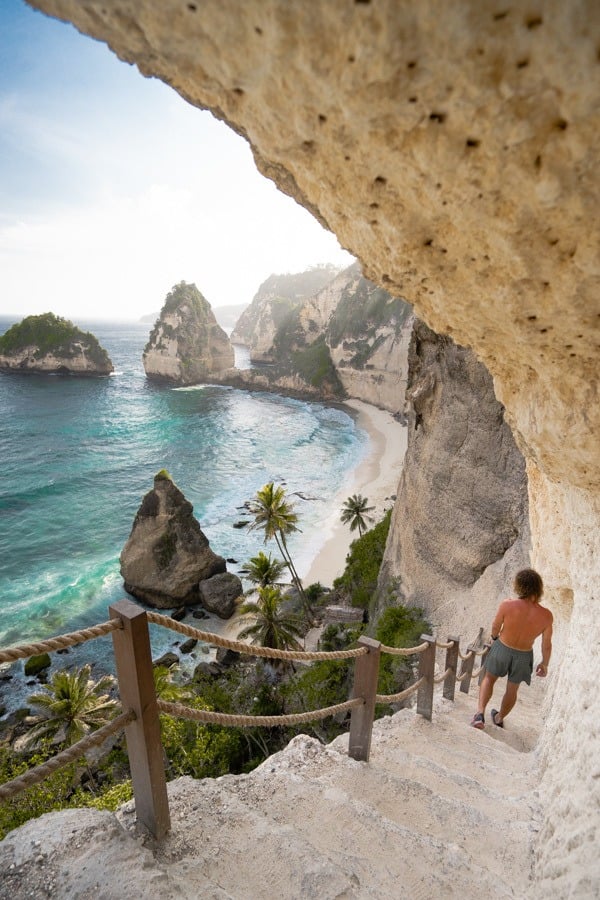 a man walking up a set of stairs next to the ocean.