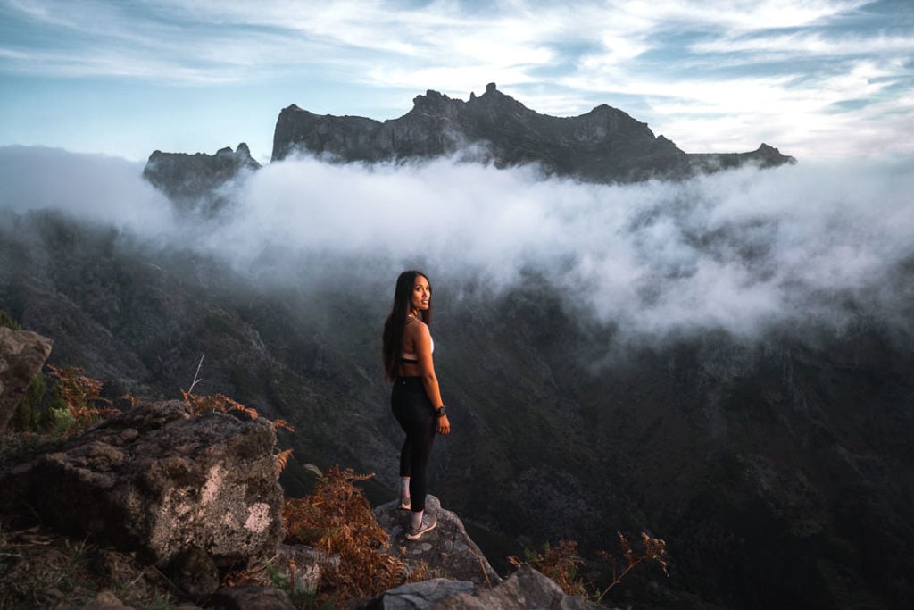 a woman standing on top of a mountain.
