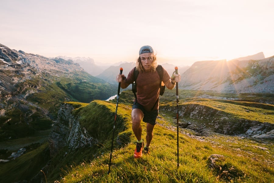 a man is hiking up a mountain with poles.
