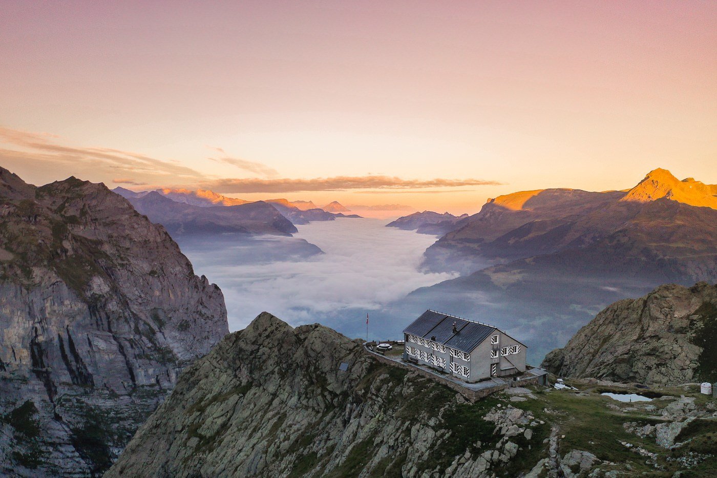 a house sitting on top of a mountain next to a valley.