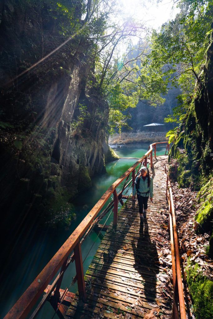 a group of people walking across a wooden bridge.
