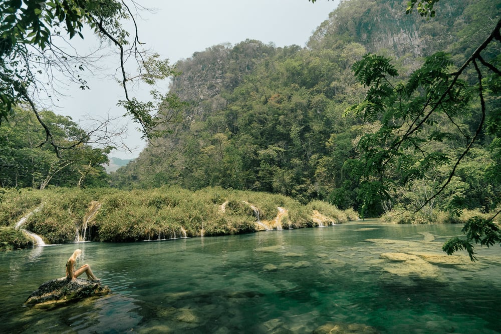 a person sitting on a rock in a river.