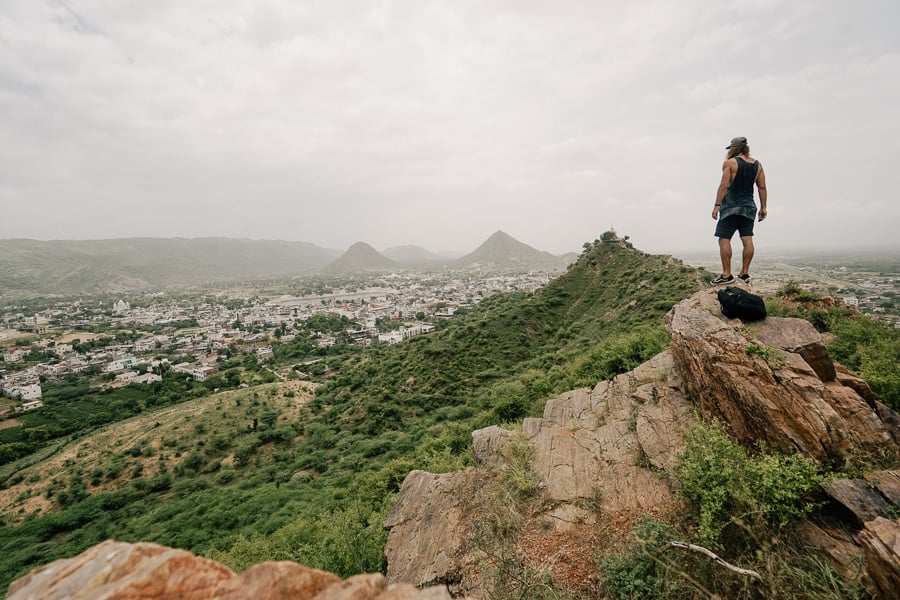 a man standing on top of a mountain with a backpack.