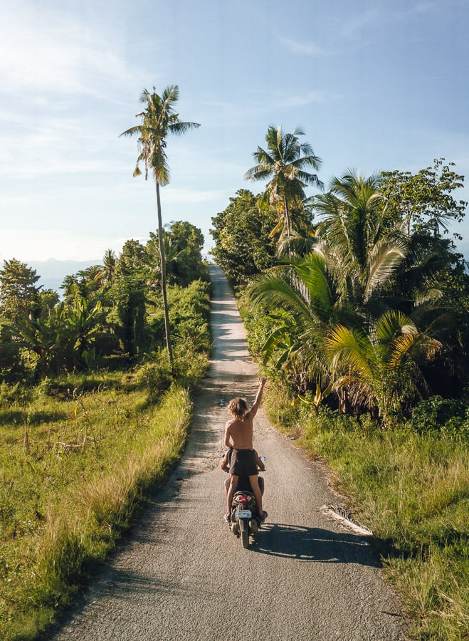 a man riding a motorcycle down a dirt road.