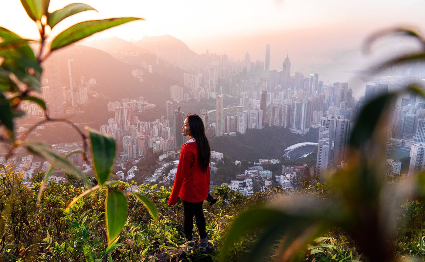 a woman standing on top of a lush green hillside.