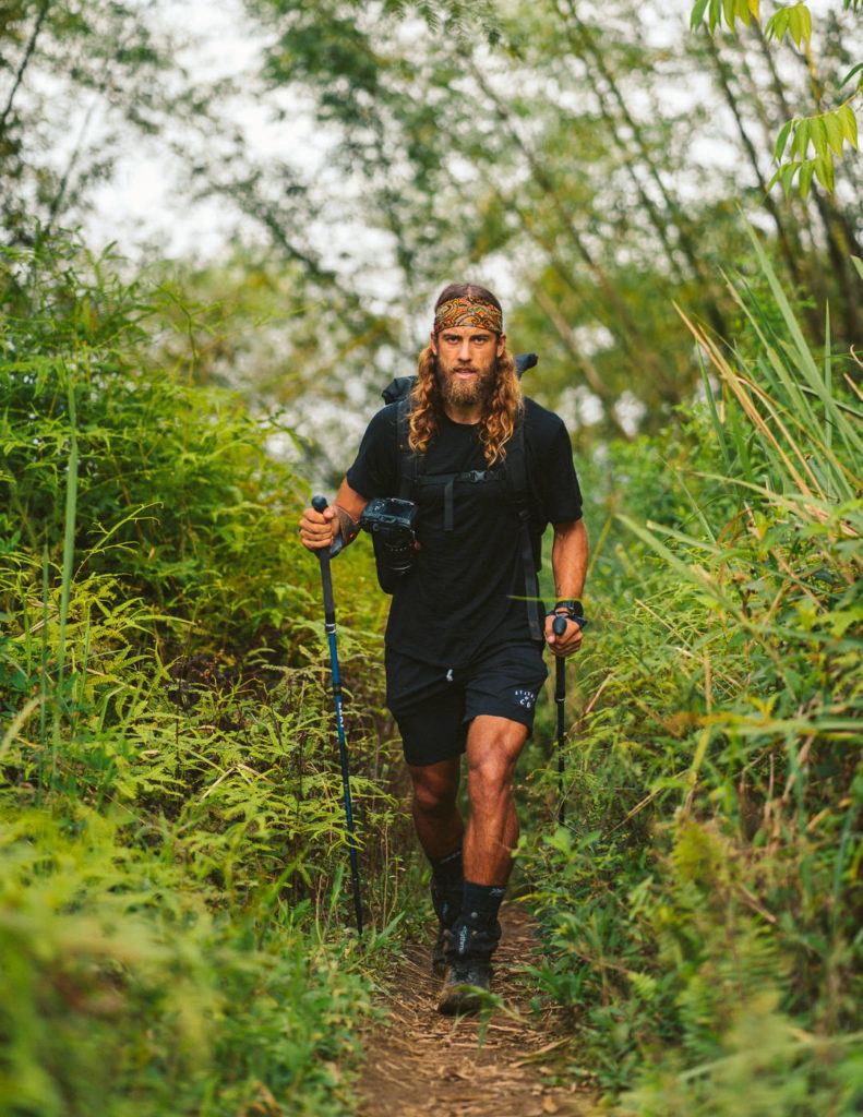 a man with long hair and a beard hiking.