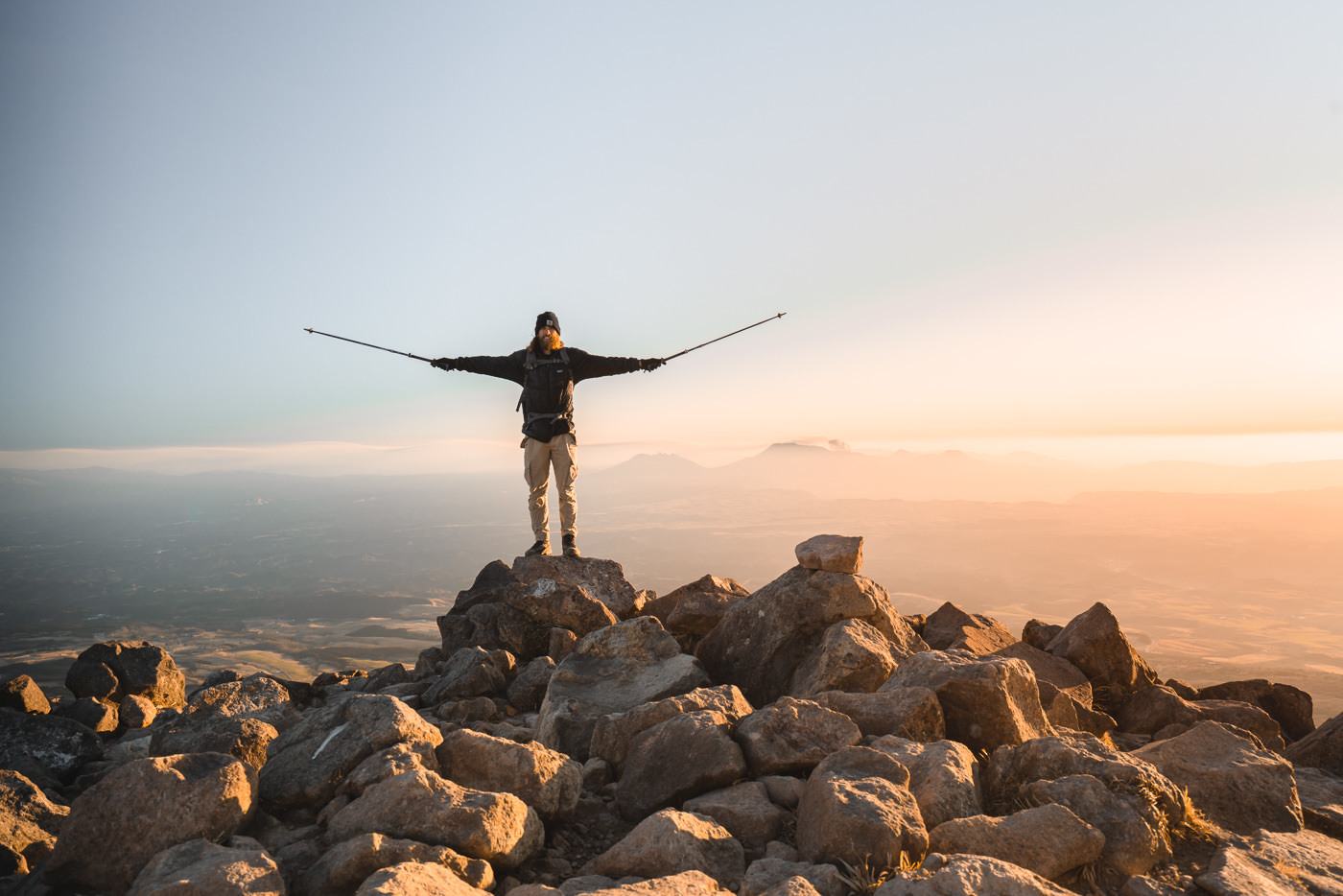 a man standing on top of a mountain holding skis.