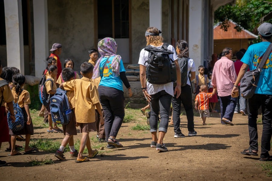 a group of people walking down a dirt road.