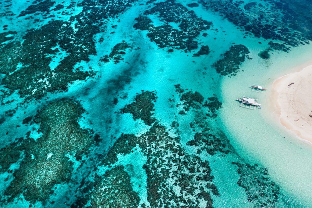 an aerial view of a beach with a boat in the water.