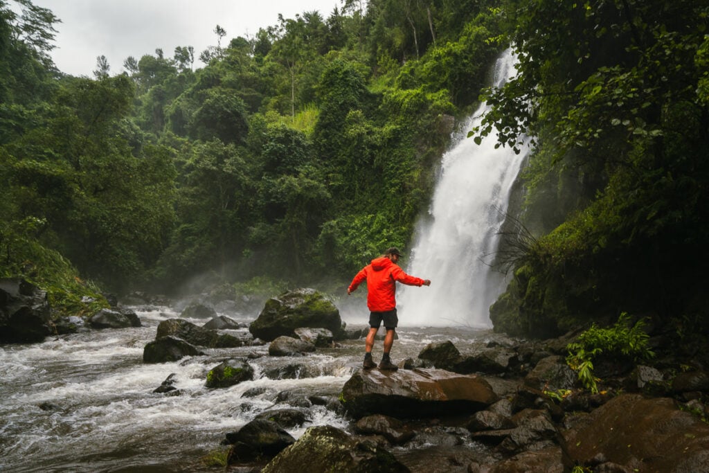 a man standing on a rock in front of a waterfall