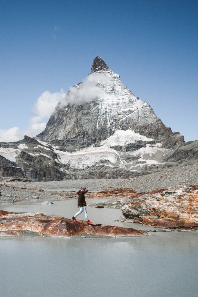 a man standing on a rock in front of a mountain.