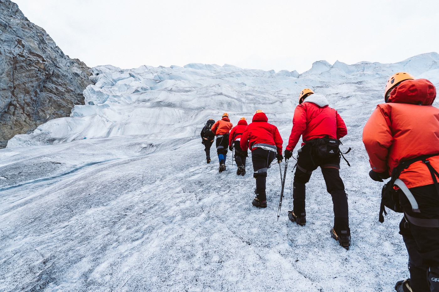 a group of people walking up a snow covered mountain.