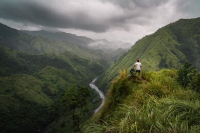 a man standing on top of a lush green hillside