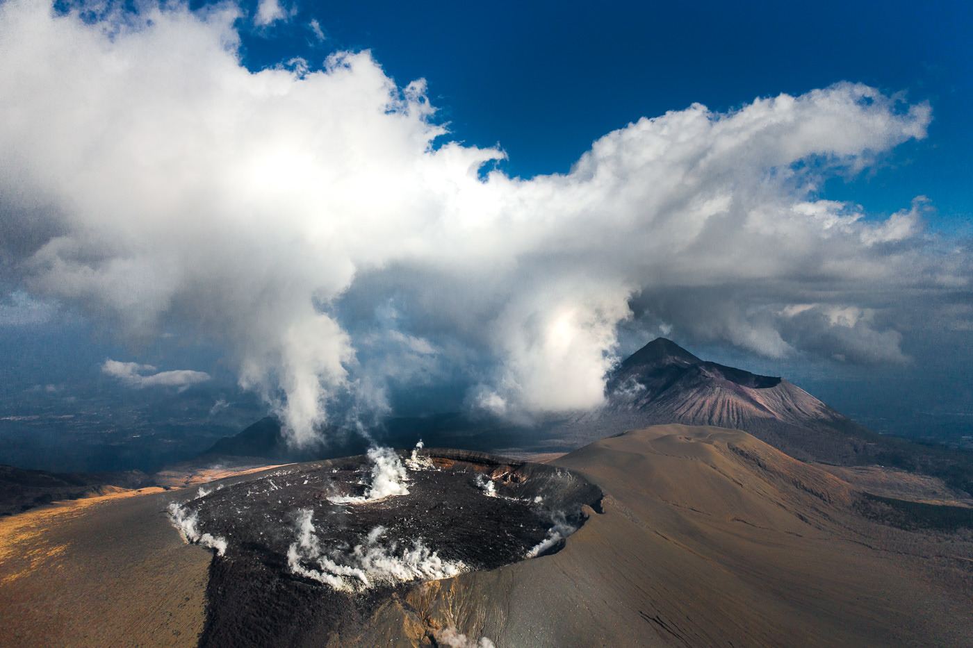 a view of a volcano with steam coming out of it.