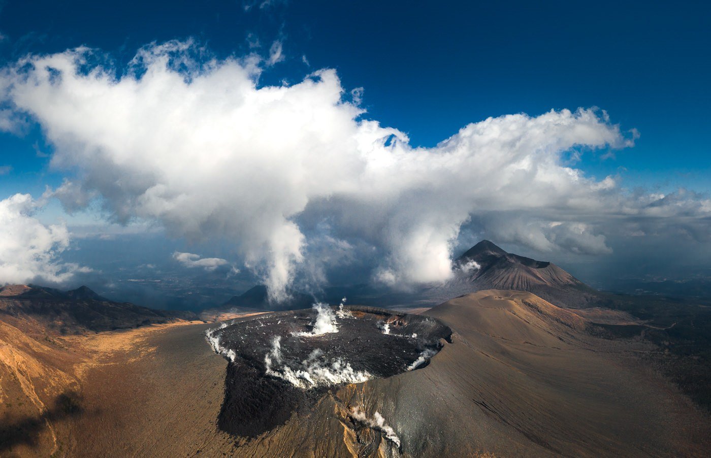 an aerial view of a volcano with steam coming out of it.