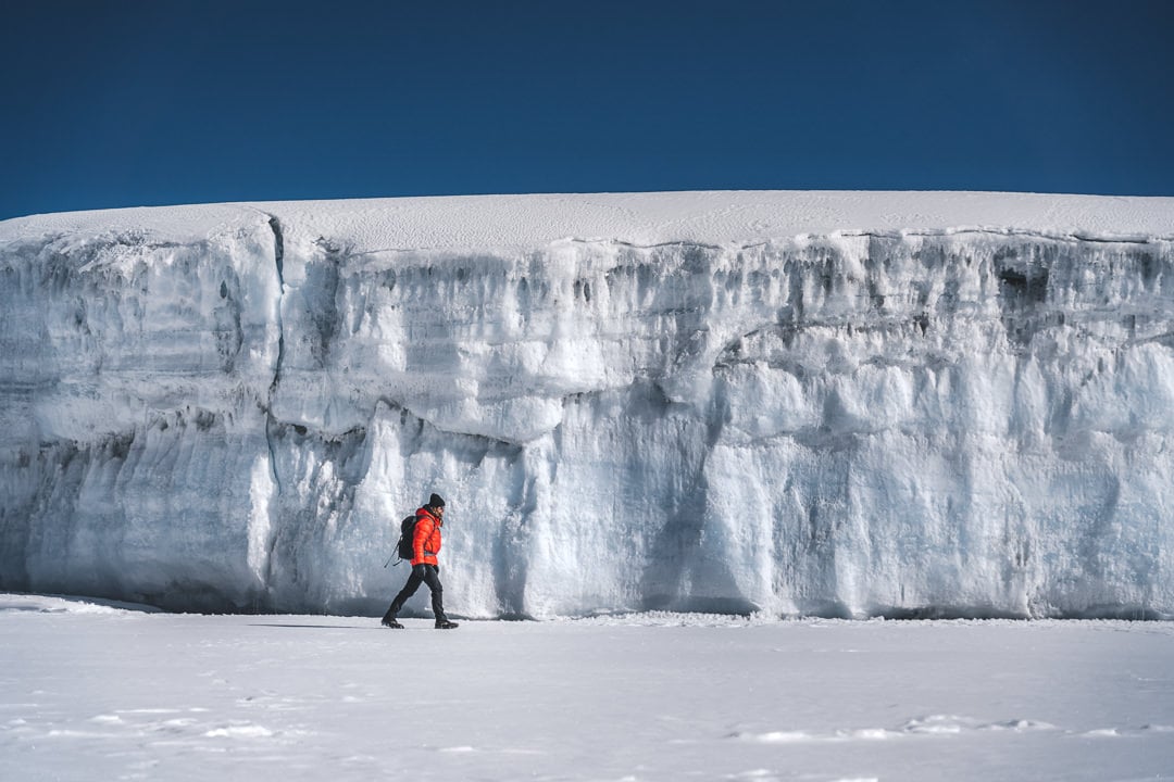 a man walking across a snow covered field.