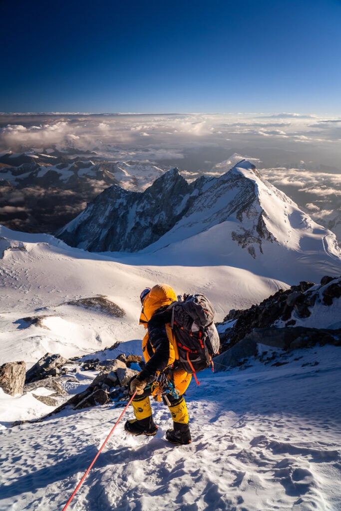 a man climbing up the side of a snow covered mountain