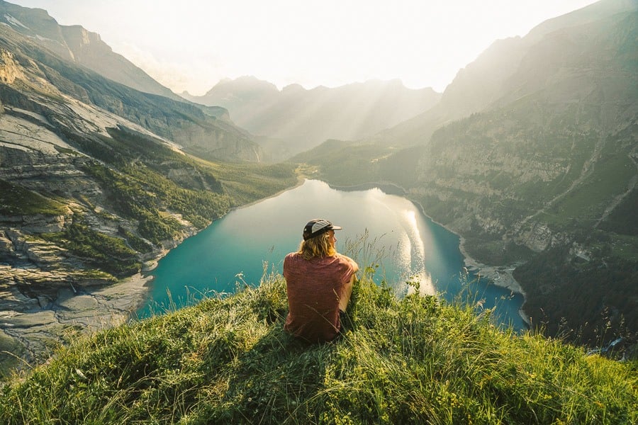 a person sitting on a hill overlooking a lake.