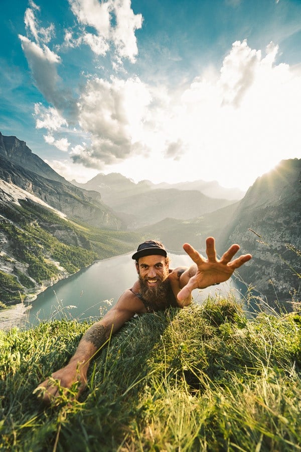 a man laying on top of a lush green hillside.