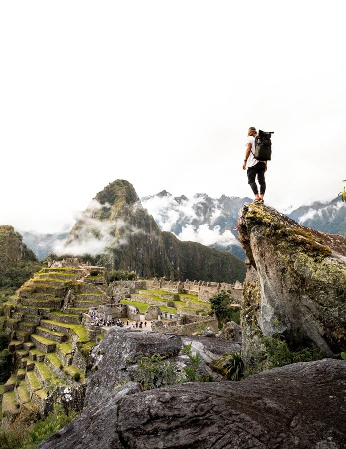a man standing on top of a rock overlooking a valley.