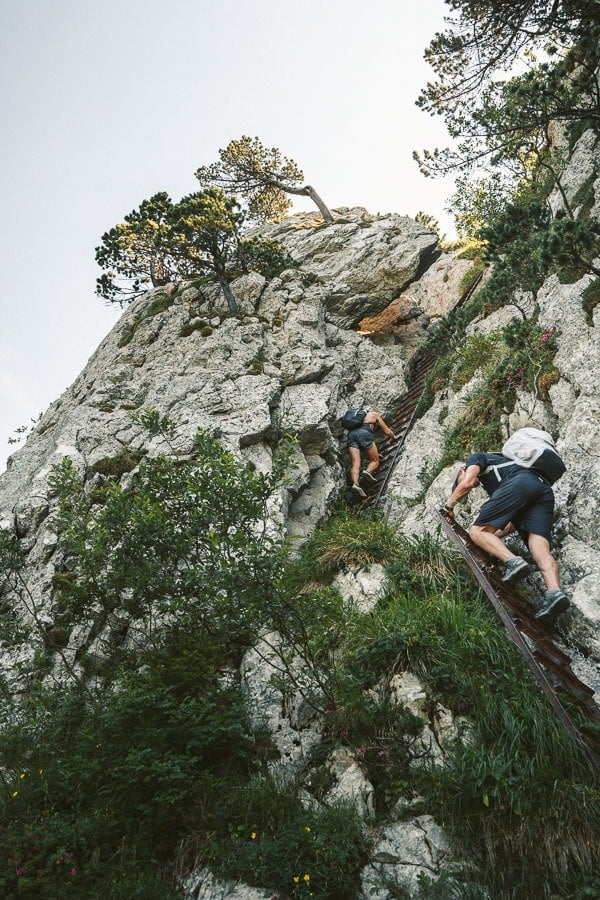 a couple of people climbing up a steep hill.