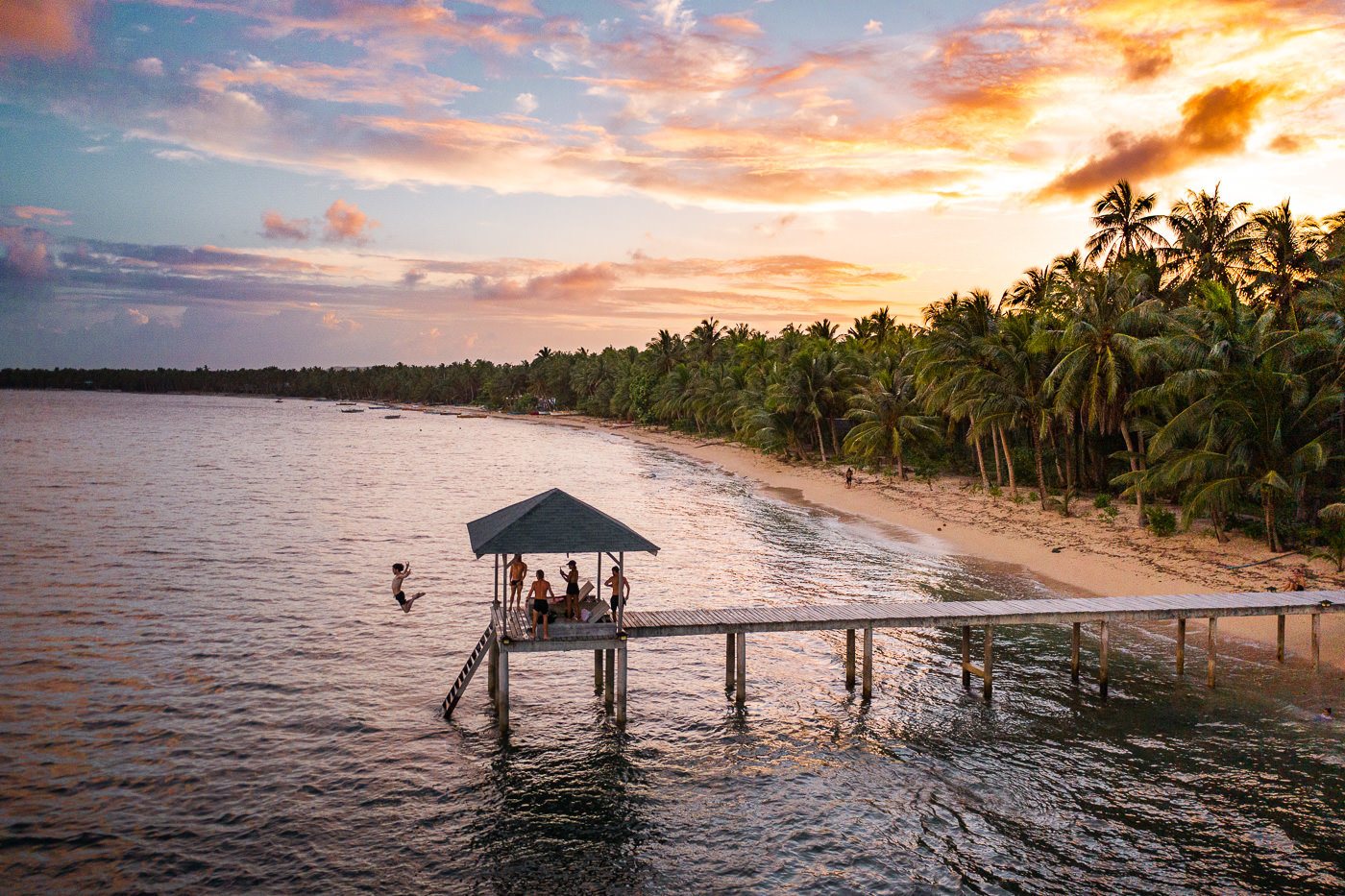 a group of people sitting on a dock next to a body of water.
