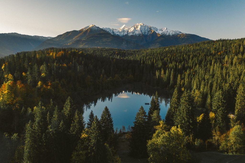 a lake surrounded by trees with a mountain in the background.