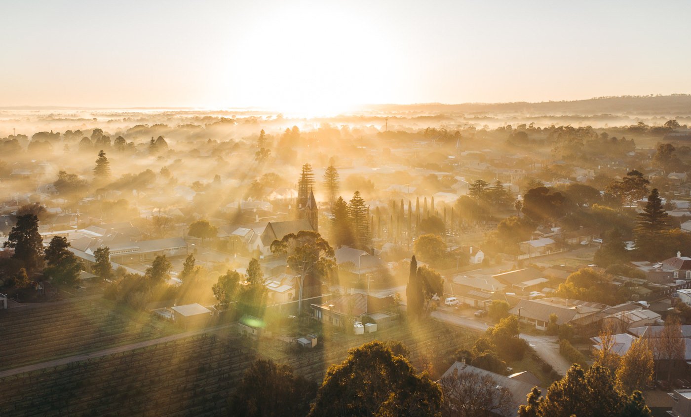 the sun is setting over a city with fog.