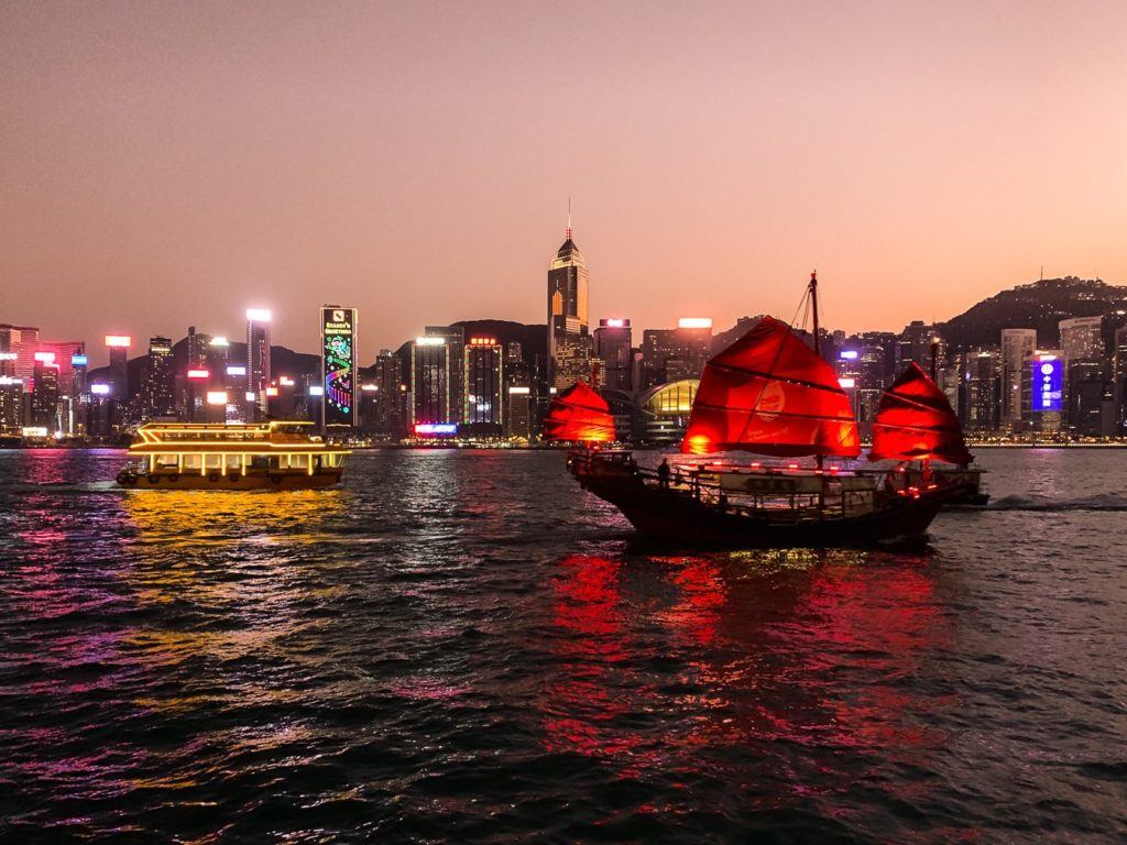a boat with red sails sailing on a body of water.