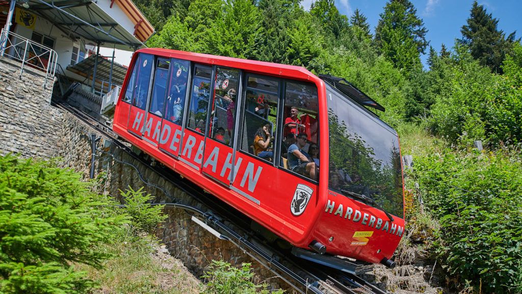 a red train traveling down tracks next to a forest.