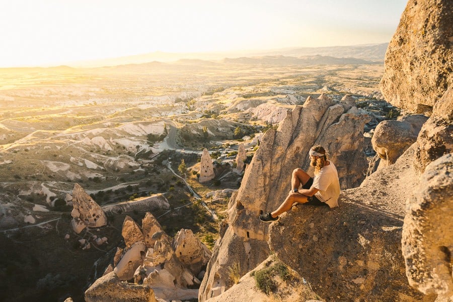a man sitting on top of a large rock.