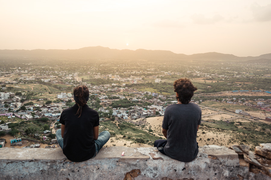 a couple of people sitting on top of a wall.
