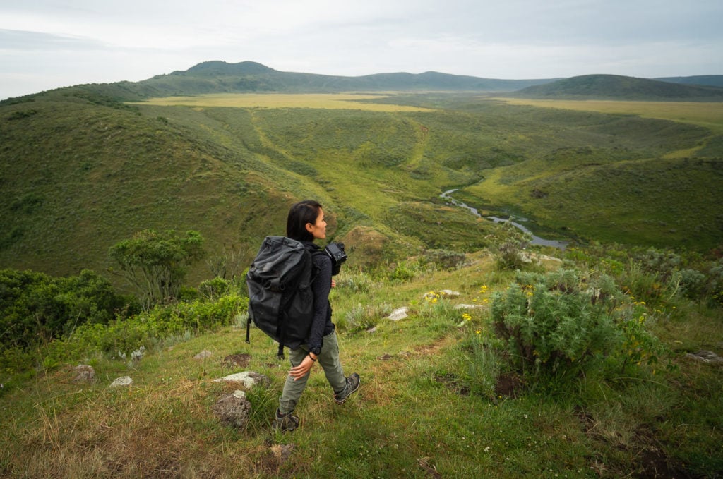 a man with a backpack is standing on a hill