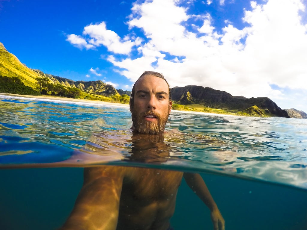 a man swimming in the ocean with a surfboard.