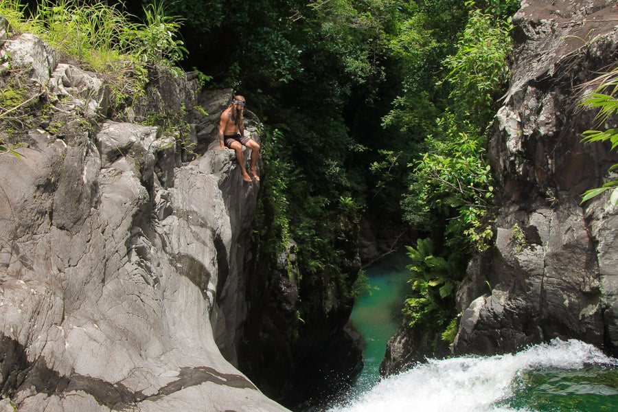 a man sitting on a rock above a river.