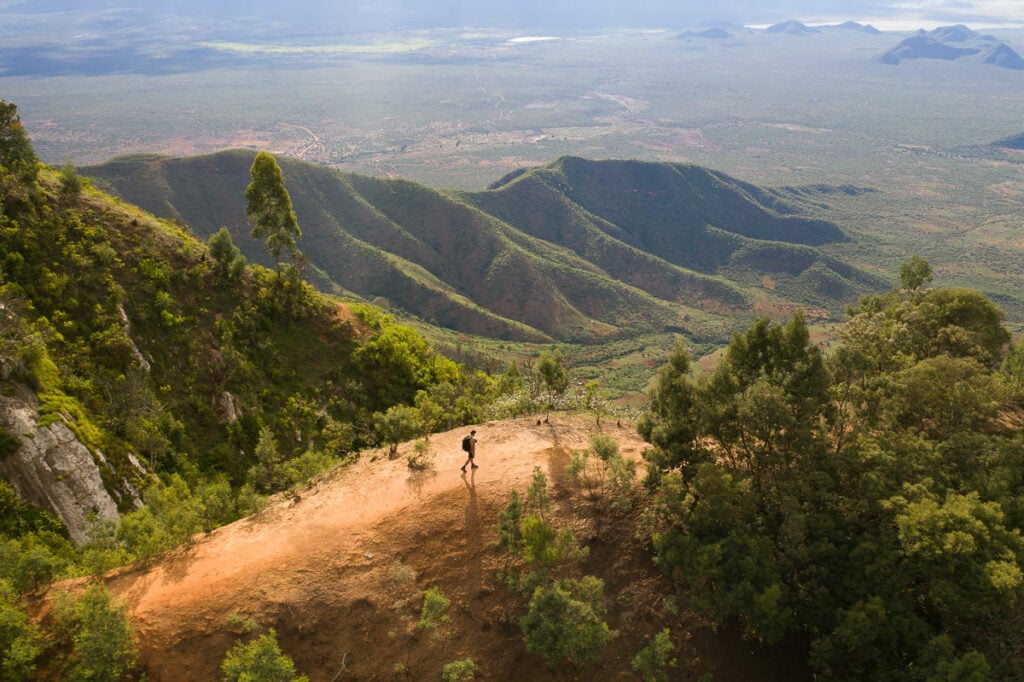a couple of people riding horses down a dirt road