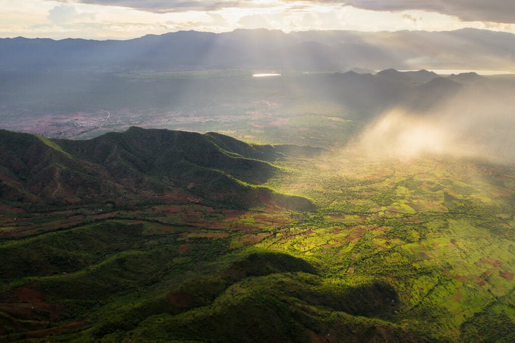 the sun shines through the clouds over a valley