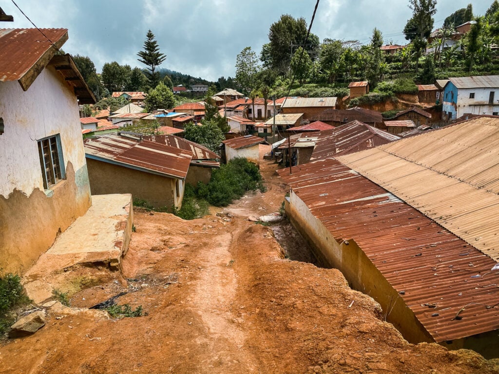 a dirt road going up a hill with houses in the background