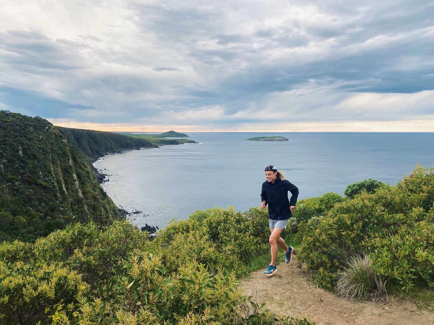 a man standing on top of a hill next to the ocean.