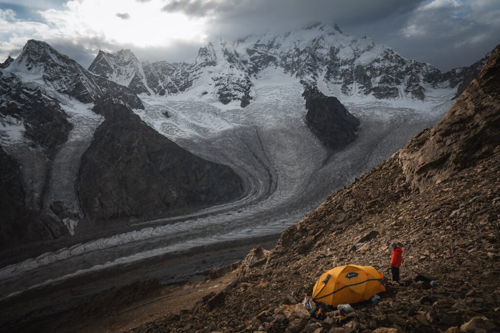 a man standing on top of a mountain next to a tent