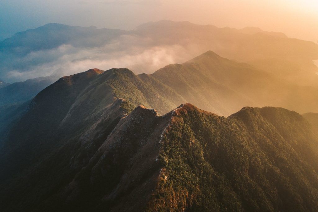 a view of a mountain range with a plane in the sky.
