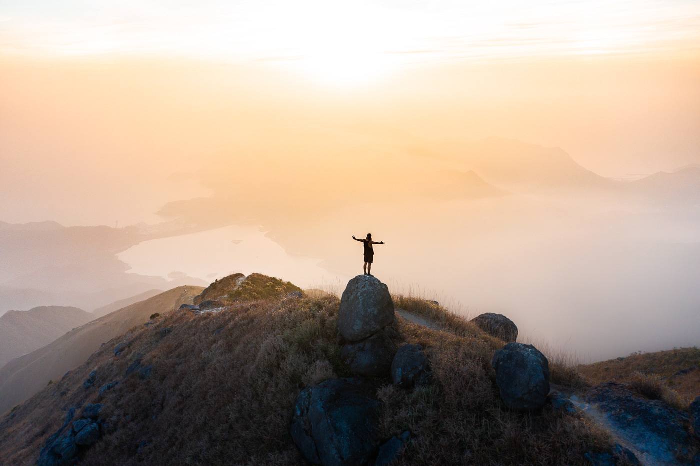 a person standing on top of a mountain at sunset.