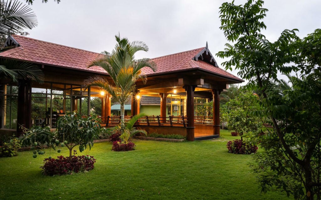 a house with a red roof sitting in the middle of a lush green yard