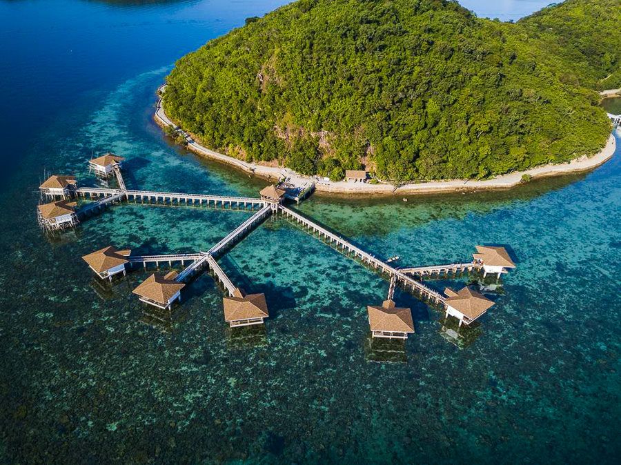 an aerial view of a resort in the middle of the ocean.