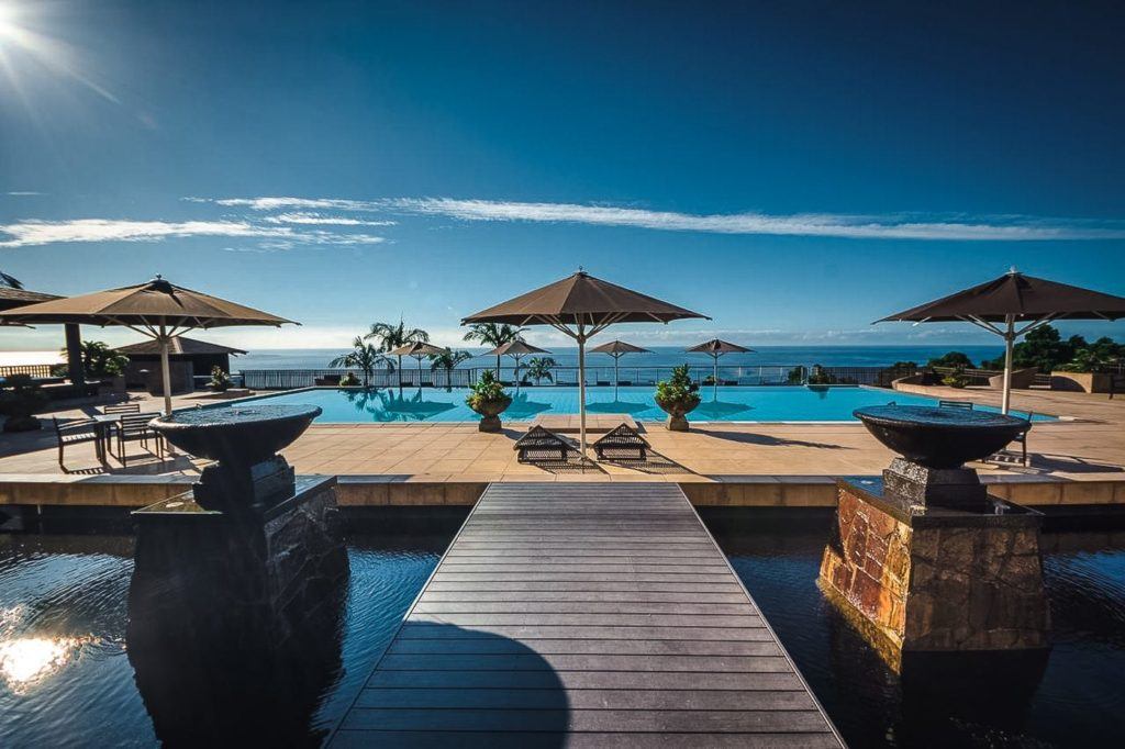 a dock with umbrellas and chairs next to a swimming pool.